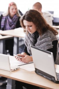 Pige med computer og mobil Digital Natives bruger flere elektroniske kanaler samtidig.